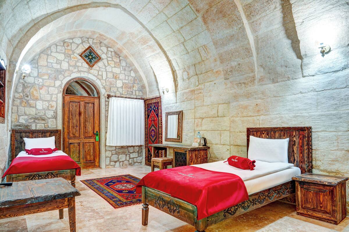 Una habitación con dos camas de madera, una pared de piedra y un escritorio de madera.