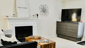 Un salon avec une cheminée, un téléviseur et un meuble.