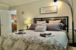 A neatly made bed with a floral bedspread, a wall sign that reads "MAKE YOURSELF AT home", and a star decoration on the wall.