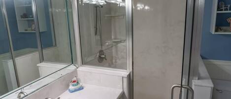 Une salle de bain moderne avec une douche à l’italienne, un lavabo blanc et un grand miroir.