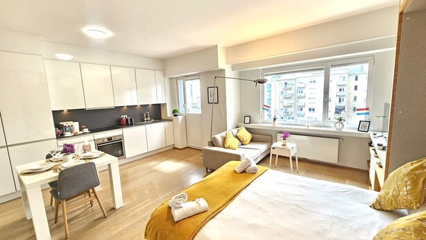 Een moderne hotelkamer met een bed, een bureau, een stoel, een klein tafeltje en een raam met uitzicht op de stad.