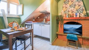 A cozy kitchen with a dining table set, a brick fireplace, and a television mounted above it.