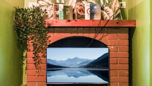 A television mounted on a brick fireplace with a view of mountains and a lake.