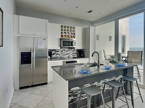 A modern kitchen with a central island, stainless steel appliances, and a view to the outside.