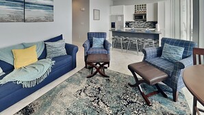 A modern living room with a blue sofa, a blue armchair, and a patterned rug. - High Seas by Ryson Vacation Rentals (Galveston)
