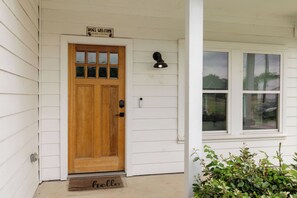 A wooden front door with a sign above it, a doormat, and a window with a view of the outside.