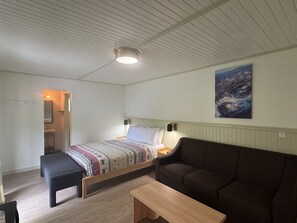 Ein Schlafzimmer mit Bett, Sofa, Bank, Nachttisch und Beistelltisch.