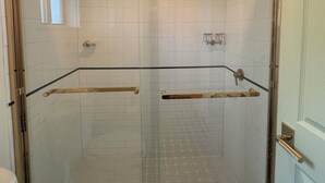 A glass-enclosed shower with a white tiled floor and a wooden handrail. - Queen Room With Balcony - NQB (Gatlinburg)