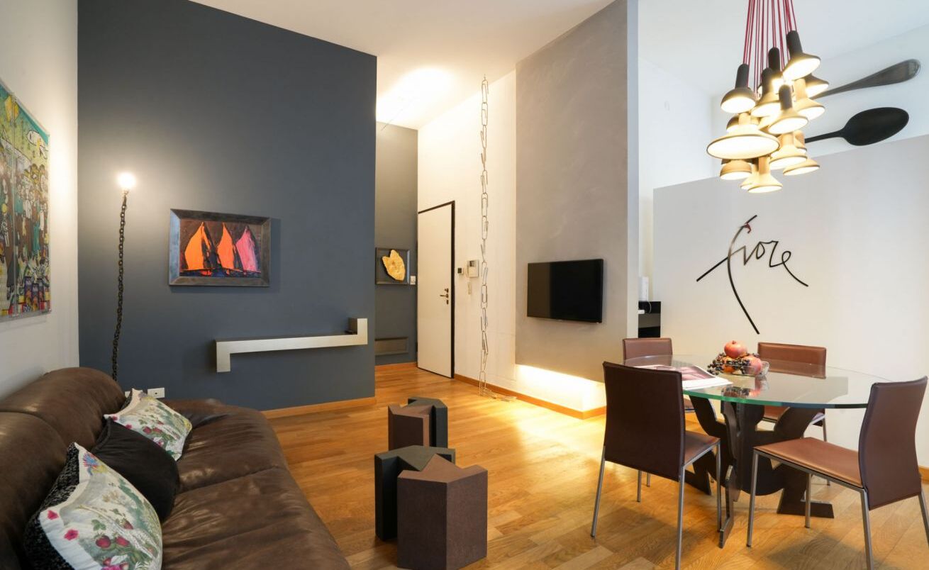 Een moderne woonkamer met een bruine leren bank, een glazen eettafel met stoelen en kunstwerken aan de wanden.