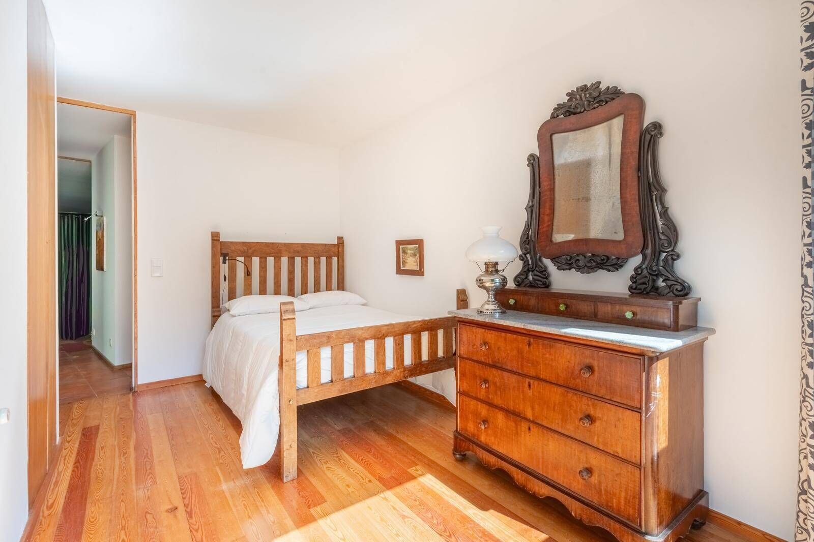 A bedroom with a wooden bed, a dresser, and a mirror.