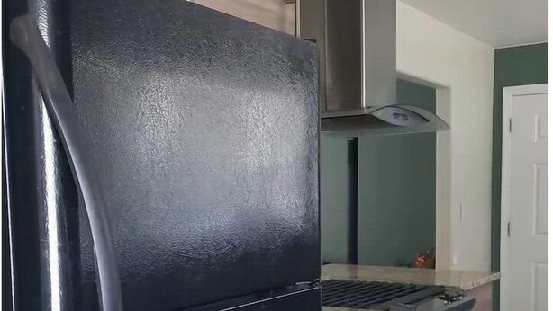 A kitchen with a black refrigerator, a stove, and a microwave.