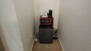 Un pasillo estrecho con un microondas y un refrigerador pequeño.