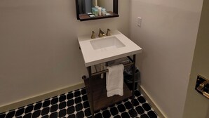 Un baño con un lavabo blanco, un espejo y un perchero para toallas.