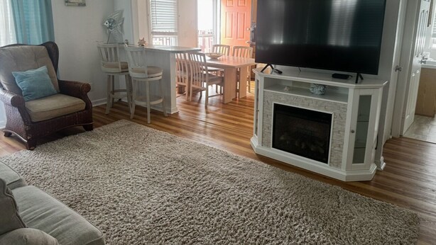 A living room with a fireplace, a television, a dining area, and a cozy seating arrangement. - Charming 2-bedroom apartment with AC, WiFi in delightful Wildwood Crest (Wildwood Crest)