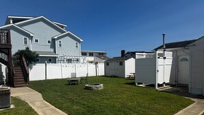 A backyard with a lawn, a stone fire pit, a wooden staircase, and a white shed. - Charming 2-bedroom apartment with AC, WiFi in delightful Wildwood Crest (Wildwood Crest)