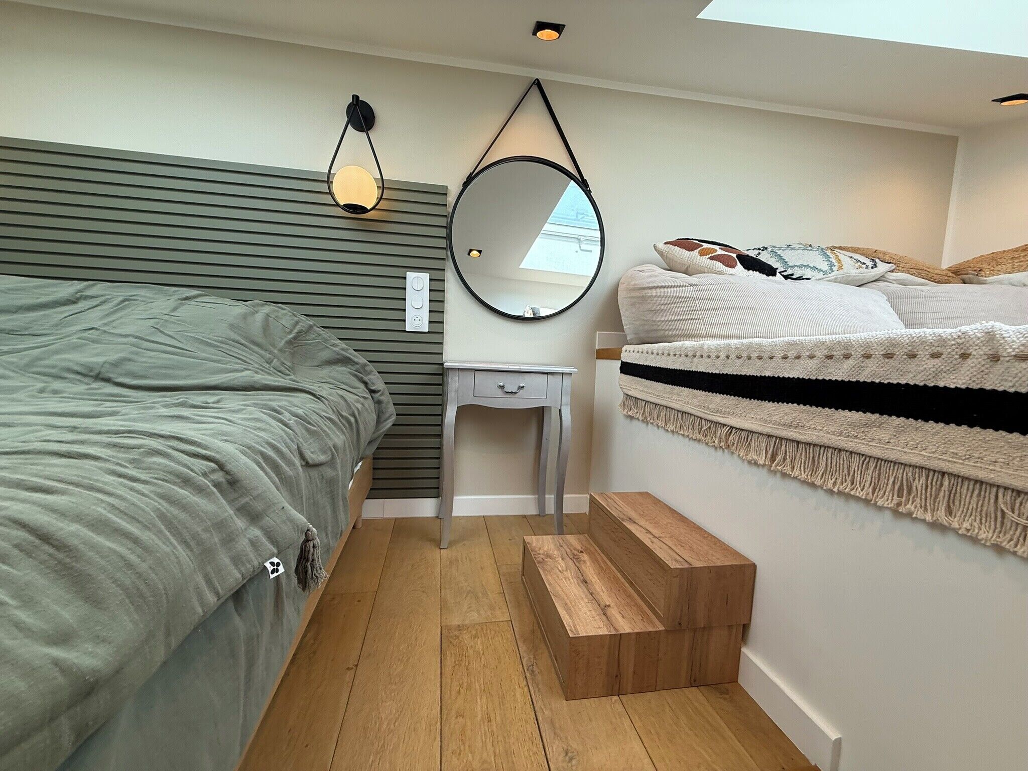 A compact bedroom with a bed, bedside table, and a small wooden bench.