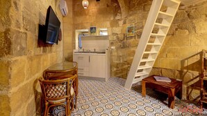 Une cuisine chaleureuse avec des murs en pierre, une table en bois et un escalier blanc.