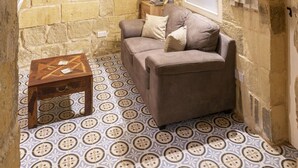 Une pièce chaleureuse avec un mur en pierre, un banc en bois, un canapé et un sol à motifs.