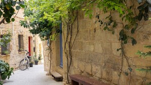 Une ruelle étroite pavée de pierres, avec un banc et un vélo.