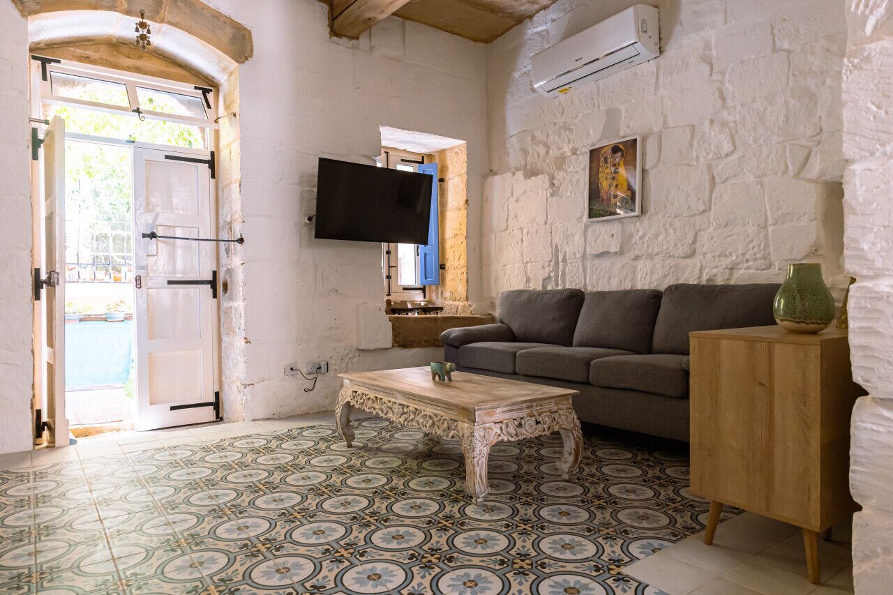 Un salon avec un canapé, une table basse et un téléviseur fixé au mur.