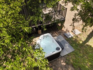 Un jacuzzi en un patio trasero con un cerco de madera y follaje.
