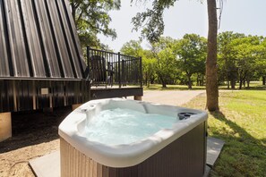 A hot tub in a garden setting with a wooden deck and metal railing. - Intimate A Frame*Hot Tub*Near Hiking & Stockyards (Fort Worth)