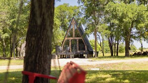 A triangular wooden cabin surrounded by trees.