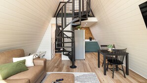 A compact living space with a spiral staircase, a sofa, a dining table, and a kitchen area.
