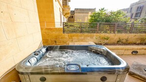 Un bain à remous doté d’un panneau de commande, entouré de murs en pierre et agrémenté d’une terrasse en bois.