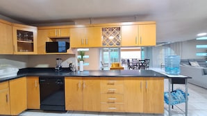 A modern kitchen with wooden cabinets, a black countertop, and a built-in dishwasher. - Cozy oceanfront condominium-2 bed in main street, 1 block away from ferry. (Cozumel)