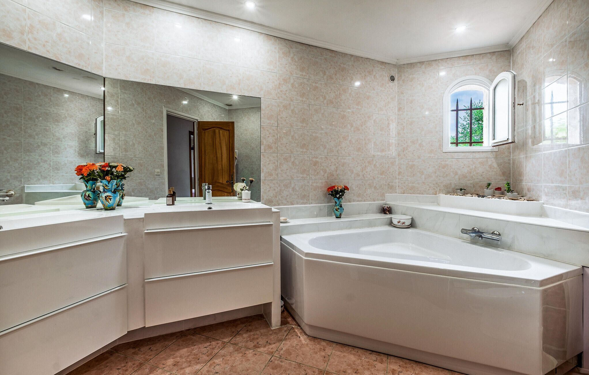 Une salle de bain moderne avec une grande baignoire, deux vasques et un miroir.