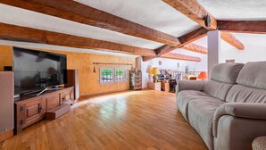 Ein geräumiger Loft mit freiliegenden Holzbalken, einem großen Flachbildfernseher und einem bequemen Sofa.