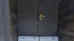 A laundry room with two white washing machines and a water heater.