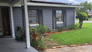A residential house with a covered porch, a small garden, and a clear sky.