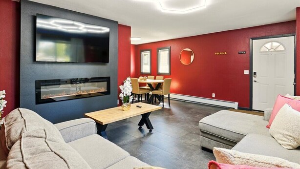 Un salon moderne avec une cheminée, un coin repas et un mur d’accent rouge.