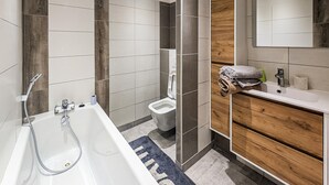 Een moderne badkamer met een bad, toilet en wastafel.