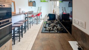 Een moderne keuken met een centraal eiland, inbouwovens en barstoelen.