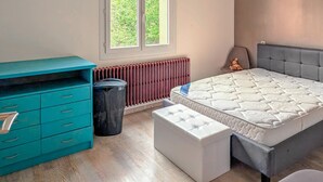 A bedroom with a bed, a dresser, a radiator, and a window with a view of greenery. - 3 bedroom stunning home in Bellaffaire (Bellaffaire)