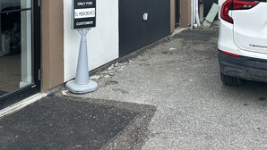 Un coche blanco aparcado frente a un edificio con un letrero que dice "ONLY FOR EL MERCADO CUSTOMER".