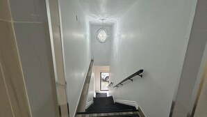 Una escalera con barandilla, un accesorio de iluminación y una puerta al final.