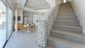 Un interior moderno con una escalera, una zona de comedor y un ventanal grande.