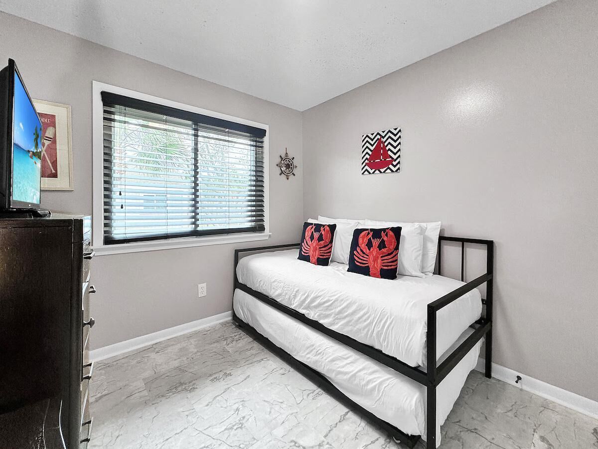 A bedroom with a bed, a window with blinds, a clock, and a wall decoration.