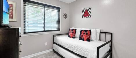 A bedroom with a bed, a window with blinds, a clock, and a wall decoration.
