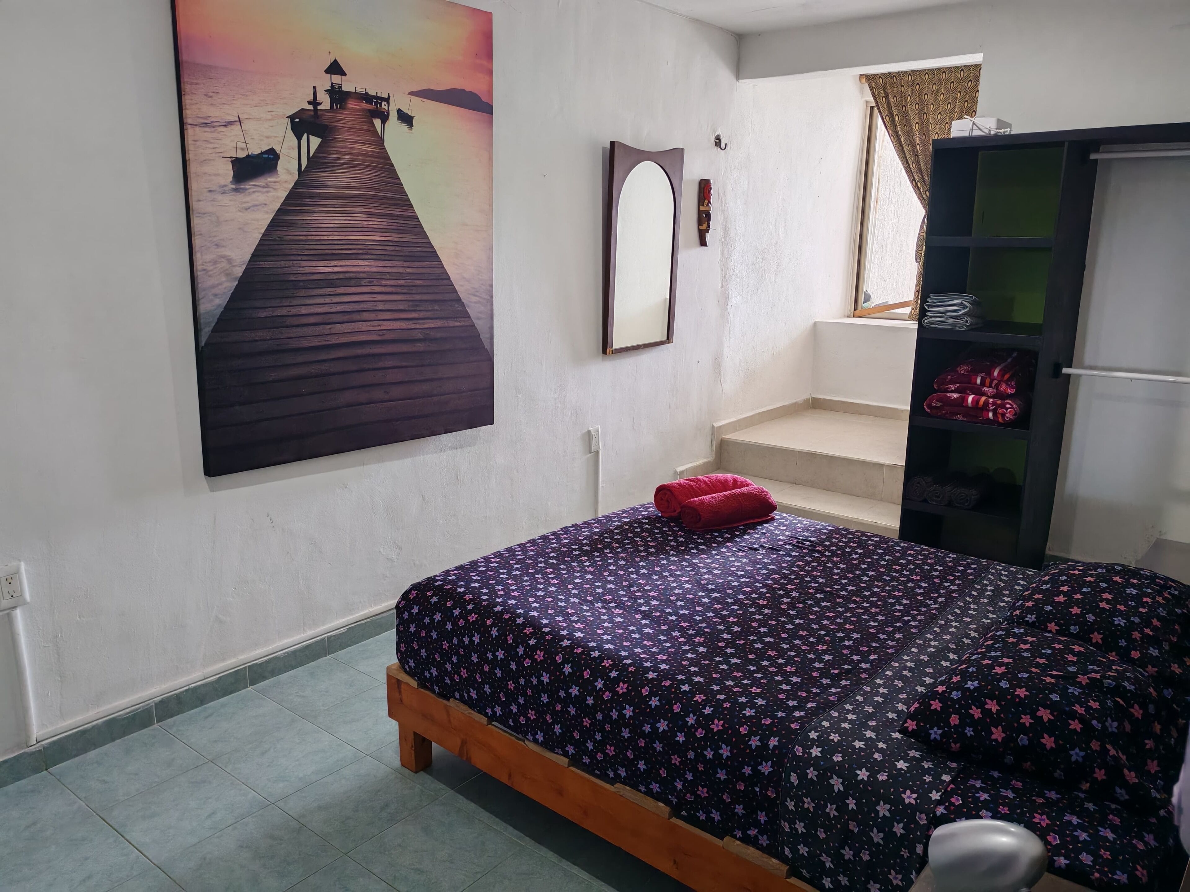 Una camera da letto con un letto, un quadro raffigurante un molo, uno specchio e un armadio.