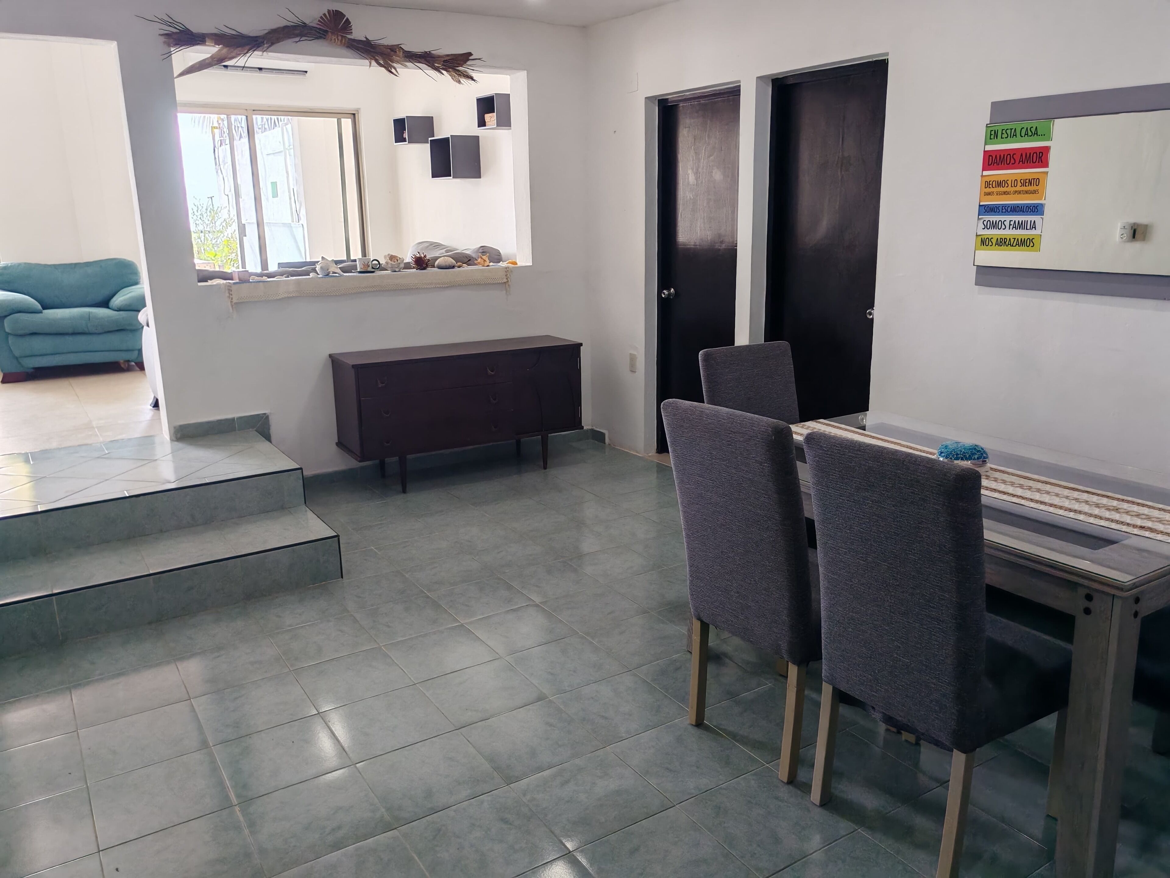 A modern interior with a dining area, a sofa, and a staircase leading to another level.
