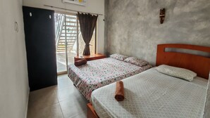 Une chambre avec deux lits, un ventilateur de plafond, un appareil de climatisation et une vue sur l’extérieur.