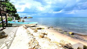 Une plage où se trouve un bateau appelé « Blanquita V » et une jetée dotée d’une structure en bois.