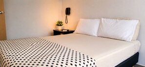 A hotel room with a bed, a bedside table with a phone, a small potted plant, and a polka dot blanket. - Cold AC fast Wi-Fi great location  (Medellín)