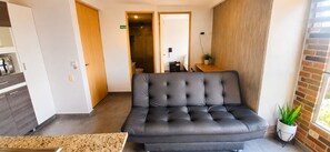 A modern hotel room with a leather sofa, a small table, and a potted plant. - Cold AC fast Wi-Fi great location  (Medellín)