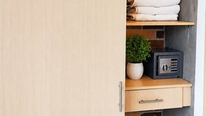 Une armoire en bois, avec un mur de briques derrière, une petite plante sur l’étagère inférieure et un coffre-fort sur l’étagère du milieu.